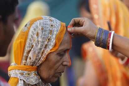 Uma mulher indiana passa na testa de uma devota o 'Tilak', um pigmento que empregado nas orações do 'Chhath Puja', à beira do rio Sabarmati, em Ahmadabad (Índia).