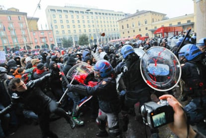 Policías y estudiantes se enfrentan ayer ante la estación de tren de Bolonia durante una manifestación contra la reforma del sistema universitario.