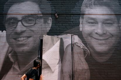 A woman steps through a door that is covered by a mural depicting American hostages and wrongful detainees who are being held abroad