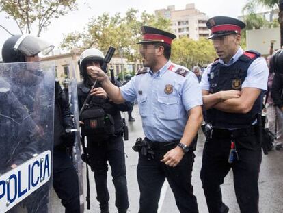 Agentes antidisturbios de la Policía Nacional y de los Mossos d'Esquadra discuten frente al Instituto Can Vilumara de L'Hospitalet de Llobregat.