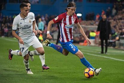 Filipe Luis (izquierda) del Atlético de Madrid es presionado por Lucas Vázquez del Real Madrid.