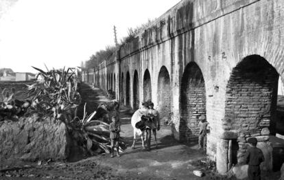 Los Caños de Carmona es un acueducto de Sevilla junto al que posan un vaquero con su vaca y unos niños en esta imagen.