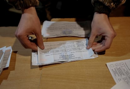 Un miembro de una comisión electoral local, en el pueblo de Zaitseve, cuenta los votos en un colegio electoral creado para los militares que participan en el conflicto con el Kremlin.