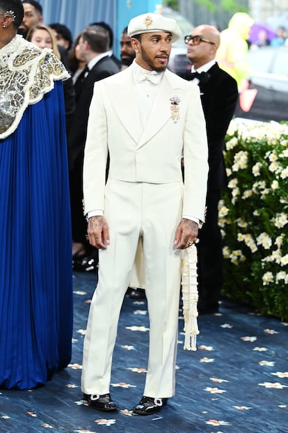 El piloto de Fórmula 1 Lewis Hamiton apostó por un traje blanco a medida y boina a juego de Louis Vuitton. La firma francesa es la patrocinadora de la exposición este año. Su director creativo, Pharrell Williams, además de ser otro de los anfitriones, es uno de los pocos diseñadores afroamericanos que han llegado a liderar una gran casa de lujo.
