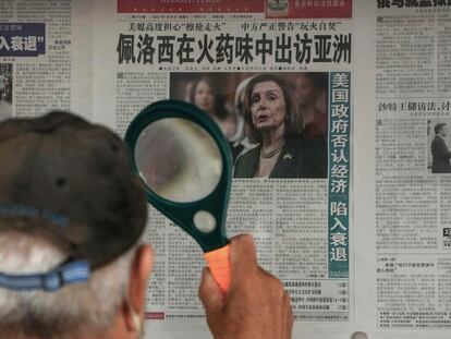 A man uses a magnifying glass to read a newspaper headline reporting on U.S. House Speaker Nancy Pelosi's Asia visit, at a stand in Beijing, Sunday, July 31, 2022. Pelosi, confirmed Sunday she will visit four Asian countries this week but made no mention of a possible stop in Taiwan that has fueled tension with Beijing, which claims the island democracy as its own territory. (AP Photo/Andy Wong)