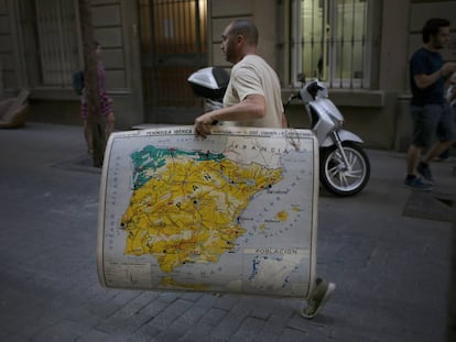 Un hombre lleva un mapa de Espa&ntilde;a mientras camina por una calle en Barcelona