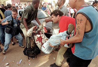 Varios hombres portan el cuerpo del fotógrafo muerto a tiros mientras cubría una protesta de los <i>sin tierra.</i>