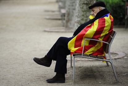 Un hombre cubierto con la bandera catalana sentado en un banco tras la consulta soberanista en el Parlamento.