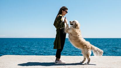 Una mujer imita un baile jugando con su labrador Retriever en un muelle.