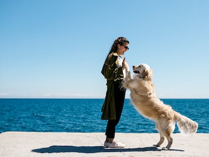 Una mujer imita un baile jugando con su labrador Retriever en un muelle.