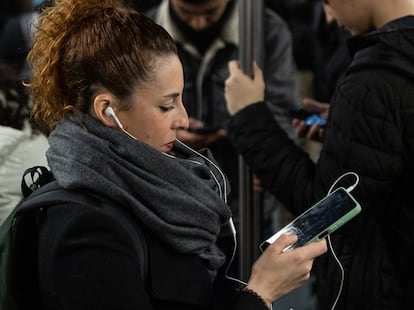 Una mujer consulta su teléfono móvil en el transporte público.
