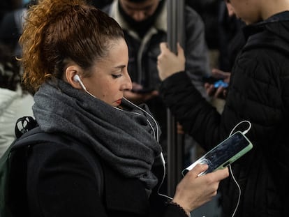 Una mujer consulta su teléfono móvil en el transporte público.