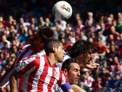 El defensa del Atlético, Álvaro Domínguez, remata el balón de cabeza ante la oposición de dos rivales del Granada.