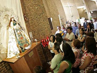 Inmigrantes peruanos rezan ante la Virgen de la Puerta en una iglesia del distrito de Latina.