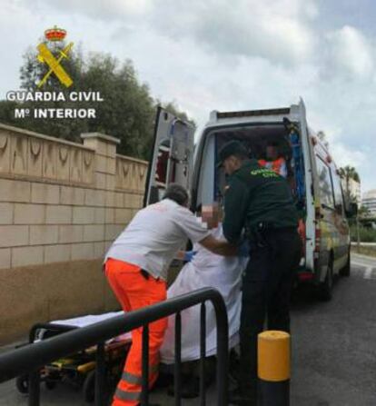 Un sanitario y un agente de la Guardia Civil trasladan el cadáver de la mujer.