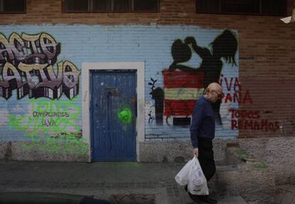 Un vecino pasea con la compra por la pintada: "Viva España. Todos remamos", que apareció hace 60 días.