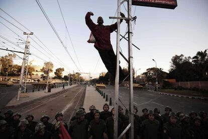 Un manifestante, encaramado a un poste y elevado sobre una de las barricadas del ejército, lanza soflamas contra Mursi.