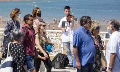 Un músico callejero sin mascarilla toca en la playa de La Concha en San Sebastián. La orden regula además el uso de las mascarillas en los eventos multitudinarios al aire libre, de modo que será obligatoria cuando los asistentes estén de pie o, si están sentados, cuando no se pueda mantener 1,5 metros de distancia entre personas.