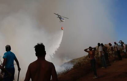 Un grupo de efectivos de la Corporación Nacional Forestal (Conaf) y de Bomberos trabajarán para intentar evitar que se reactiven los focos del incendio. En la imagen, un helicóptero arroja agua sobre las llamas.