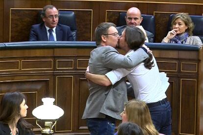Captura de televisión en la que aparecen el líder de Podemos, Pablo Iglesias (d), y el de En Comú Podem, Xavier Doménech, celebrando su estreno en la tribuna de oradores de la Cámara Baja con un efusivo abrazo y un beso en los labios.