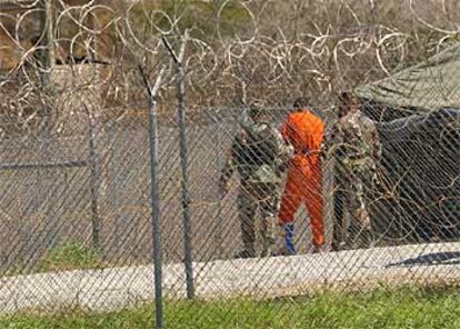 Uno de los detenidos en Guantánamo, con una pierna escayolada, es trasladado por militares de EE UU a su celda.