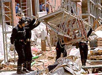 Los bomberos retiran el pasado lunes los escombros que había sobre el cuerpo de uno de los obreros fallecidos.