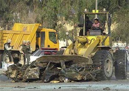 Un <i>bulldozer</i> retira coches calcinados del lugar donde ayer estalló un todoterreno cargado con 500 kilos de explosivo.