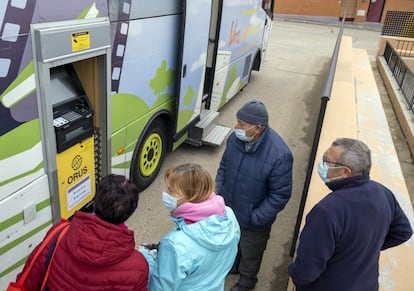 Varios usuarios contemplan el cajero automático instalado en un bibliobús en Aldearrubia (Salamanca).