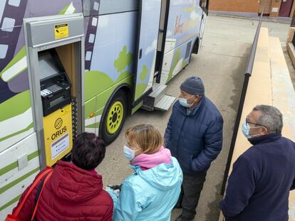 Varios usuarios contemplan el cajero automático instalado en un bibliobús en Aldearrubia (Salamanca).