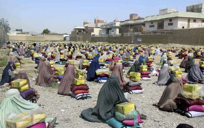 Mujeres afganas ataviadas con burka reciben paquetes con ayuda que fueron repartidos por la ONG Ummah Welfare Islamic en Kandahar (Afganistán).