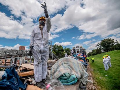 Trabajadores ferroviarios con mascarillas recogen basura dejada por personas sin hogar en las vías del tren en Bogotá.