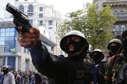 Un activista prorruso apunta con una pistola a partidarios del gobierno ucranio durante los enfrentamientos de hoy en las calles de Odessa.