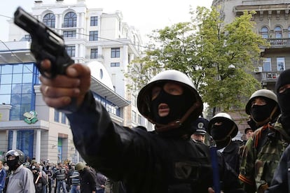 Un activista prorruso apunta con una pistola a partidarios del gobierno ucranio durante los enfrentamientos de hoy en las calles de Odessa.