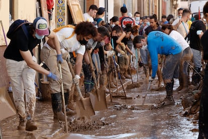 Varias personas retiran el lodo acumulado en una calle de la localidad valenciana de Paiporta, este sábado.