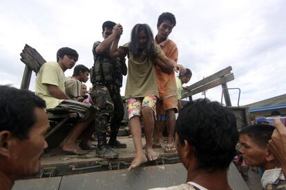 Varias personas que fueron rescatadas  de sus casas  inundadas son ayudadas por los militares en New Bataan, provincia del Valle de Compostela, al sur de Filipinas. 