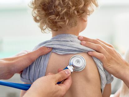 Unrecognizable male pediatrician examining curly little patient with help of stethoscope, blurred background