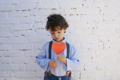 Un niño triste sujeta un corazón.