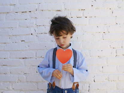 Un niño triste sujeta un corazón.