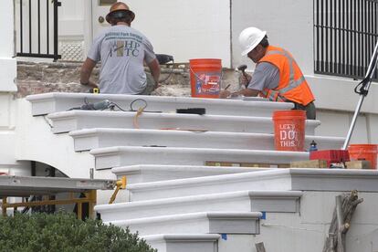 Dos operarios trabajan en la renovación de las escaleras del Pórtico Sur.