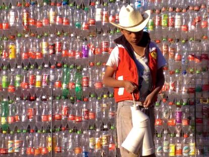 Un niño, frente a una pared de botellas de plástico en tetela, México.