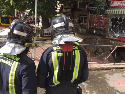 Dos bomberos observan el socavón de la avenida del Marqués de Corbera.