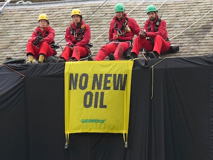 Greenpeace activists sit on the roof of Britain's Prime Minister Rishi Sunak's house in Richmond, North Yorkshire, England, after covering it in black fabric, Thursday Aug. 3, 2023.