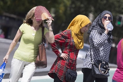  Varias personas se protegen del sol y la temperatura con un abanico y bebiendo agua, en Sevilla.