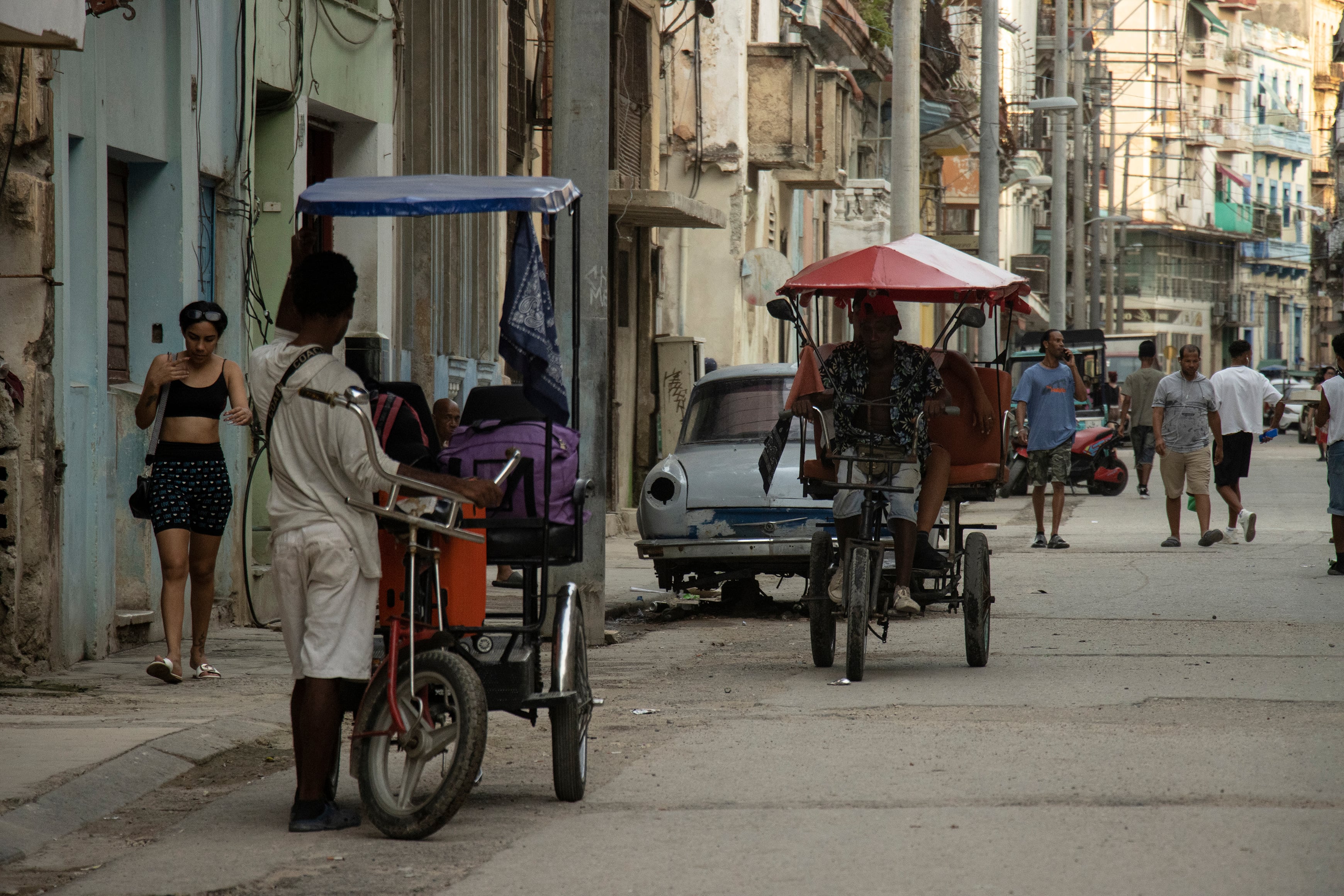 Personas se transportan en triciclos en el centro de La Habana.