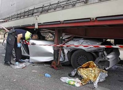 Un policía local de Leganés inspecciona el Seat Córdoba que se estrelló contra un remolque.