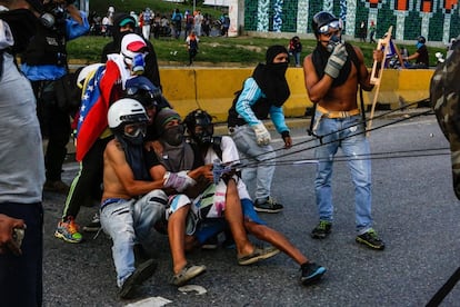 Unos jóvenes se enfrentan a los militares lanzando objetos frente a la base militar de La Carlota en Caracas.