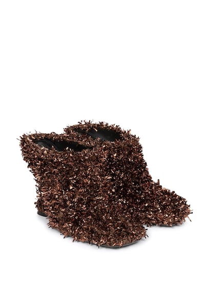 Dries van Noten presenta su propia versión de zapatos “peludos”, en clave mucho más festiva. Lo consigue forrando estos botines de cuña con un poliéster metalizado que recuerda al espumillón que decora los árboles de Navidad. (650 euros).