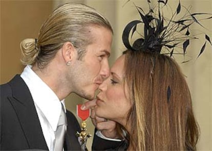 El jugador besa a su esposa tras recibir la medalla de la Orden del Imperio Británico.