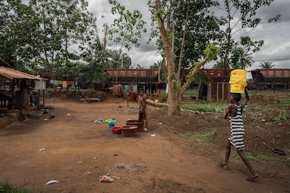 Un tren cargado de bauxita pasa por el pueblo de Kolaboui, a pocos metros de la casa de Adama Keita, mientras una joven lava la ropa.