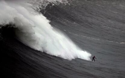 Un surfista navega una gran ola en Praia do Norte en Nazare, Portugal.